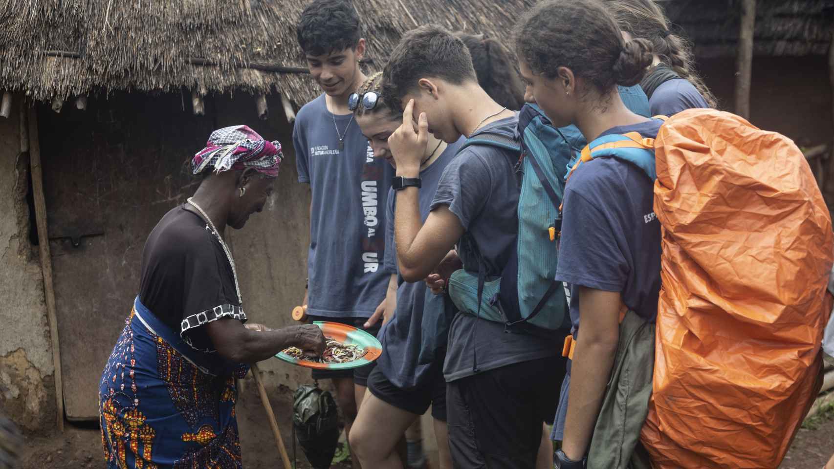 Unos jóvenes escuchan atentamente a las explicaciones de una mujer en Senegal.