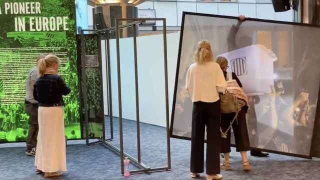 Un funcionario de la Eurocámara retira la imagen de la urna del 1-O en la exposición de Puigdemont