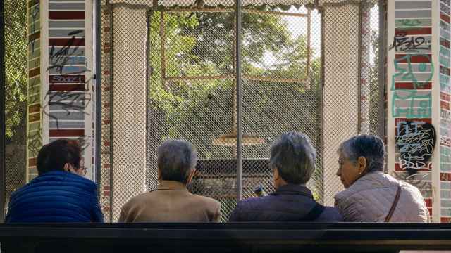 Mujeres conversan sentadas en un banco en Orense.