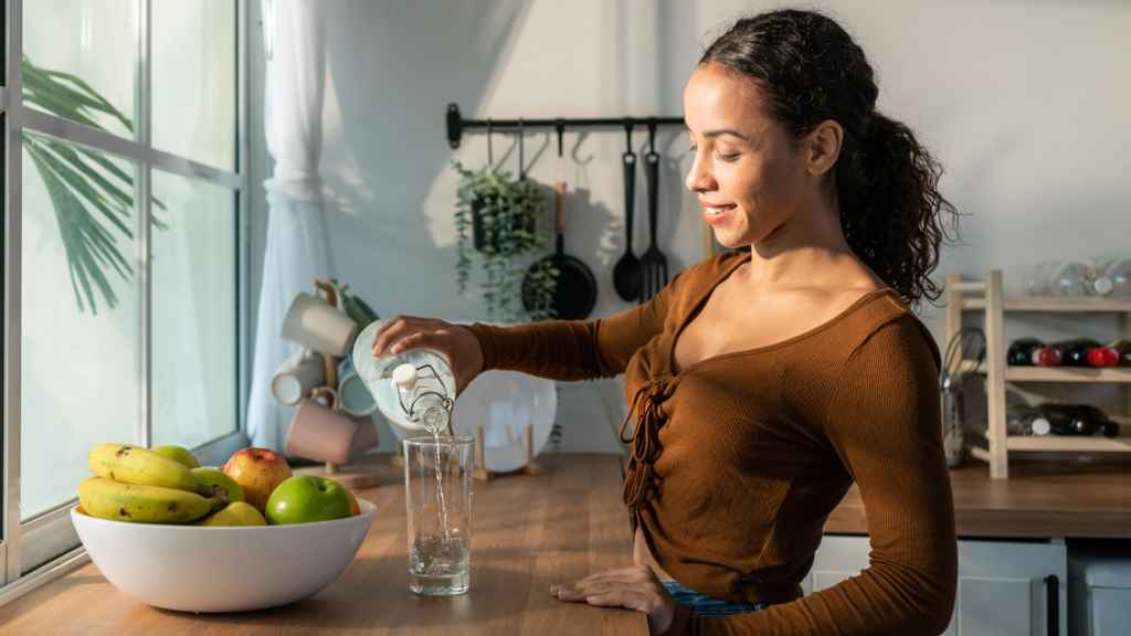 Una mujer bebiendo agua por la mañana.