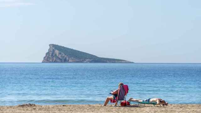 Una pareja disfruta tomando el sol en una playa de Benidorm, Alicante.