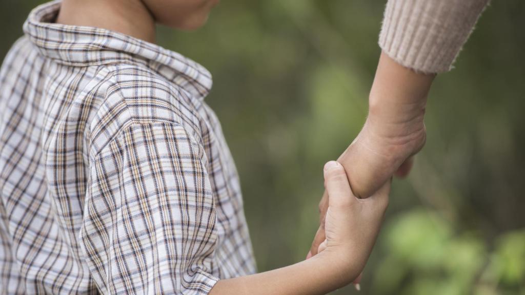 Un niño de la mano de su madre.