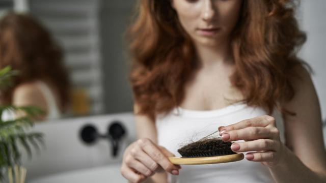 Mujer con cepillo para el cabello en el baño. Foto: iStock.