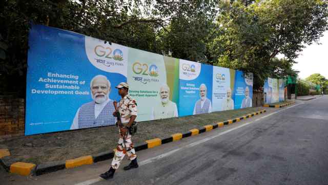 Un miembro del personal de seguridad patrulla una calle de Nueva Delhi frente a carteles que anuncian la cumbre del G20, este viernes.