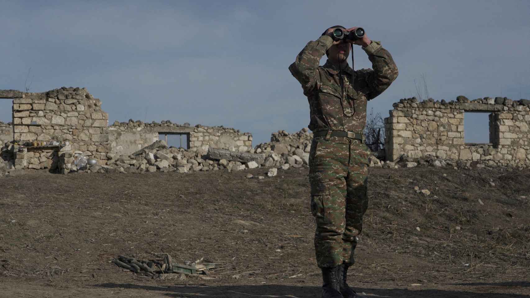 Un soldado de etnia armenia mira a través de binoculares mientras se encuentra en posiciones de combate en la región de Nagorno-Karabaj.
