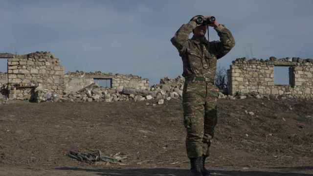 Un soldado de etnia armenia mira a través de binoculares mientras se encuentra en posiciones de combate en la región de Nagorno-Karabaj.