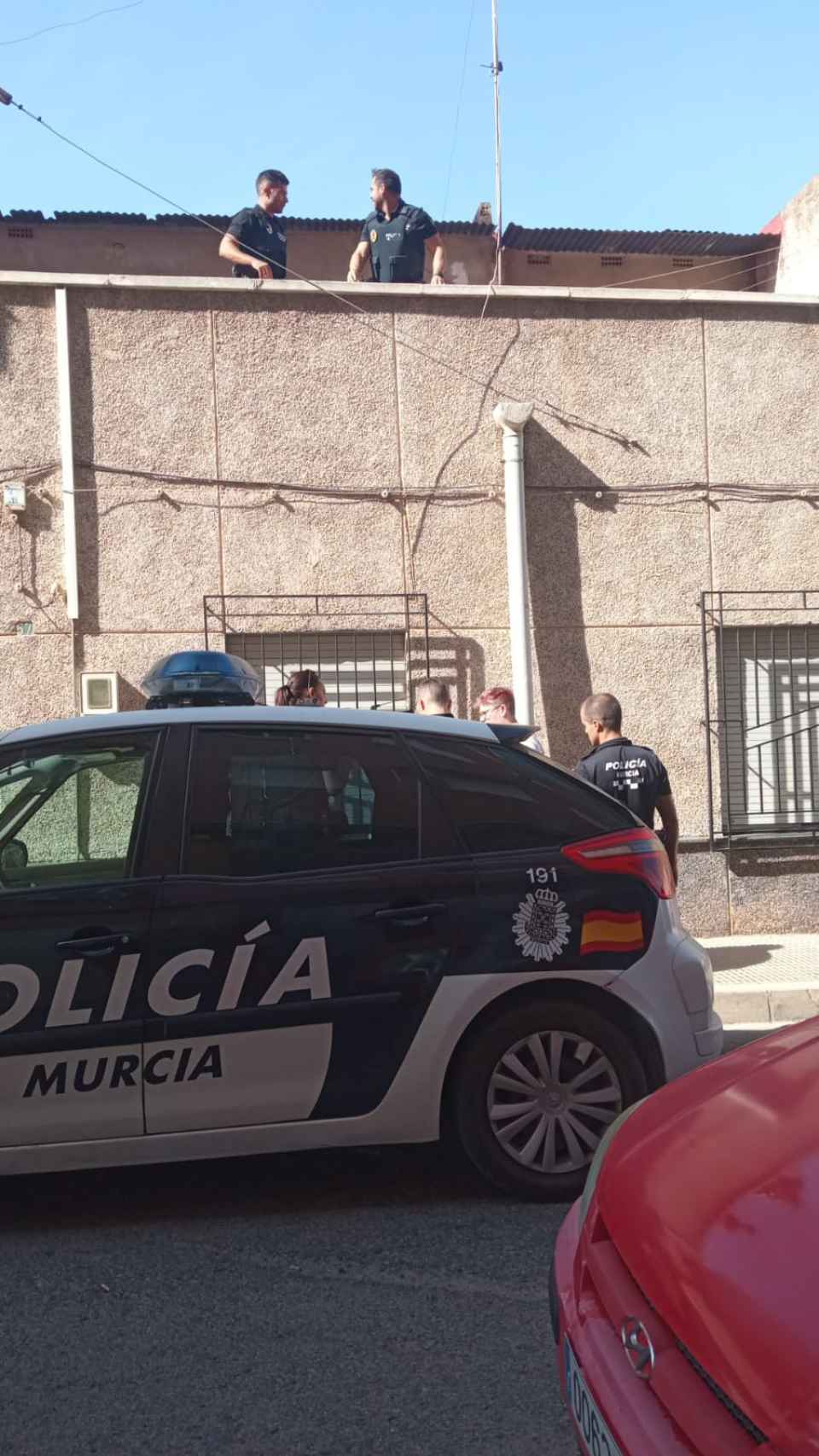 Unos policías locales, este domingo, custodiando al hijo de Maravillas que luce gafas y pelo rosa.