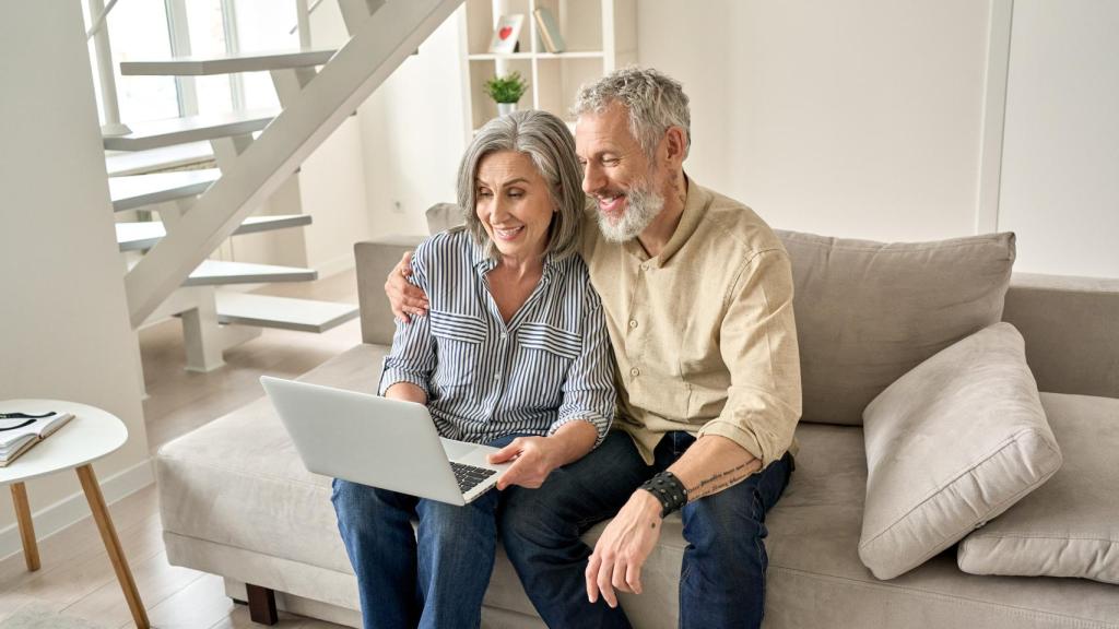 Una pareja mayor sonríe feliz en el salón de una vivienda, en una imagen de archivo.