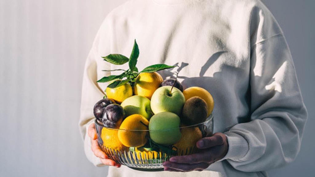 Imagen de una mujer sosteniendo un bol de fruta.