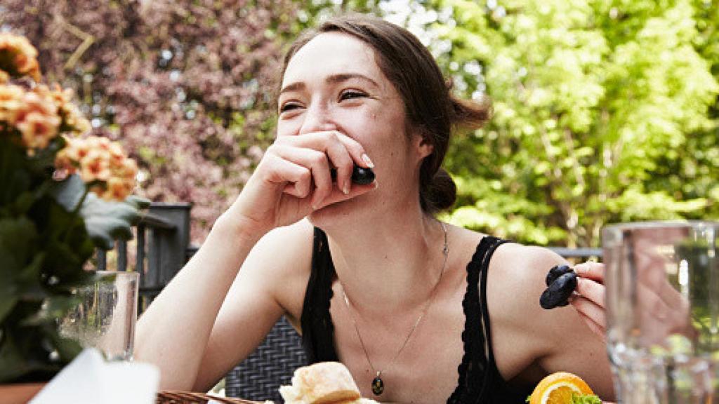 Imagen de una mujer comiendo sonriente.