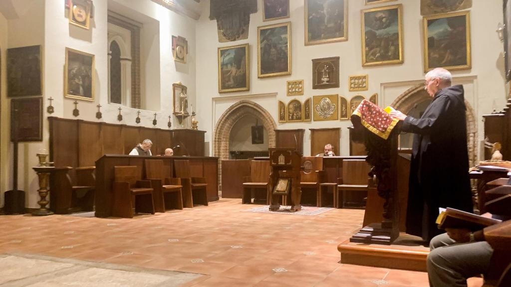 El monje benedictino fray Martín (d) lee una oración en la capilla, donde se celebran todas las liturgias religiosas a lo largo del día