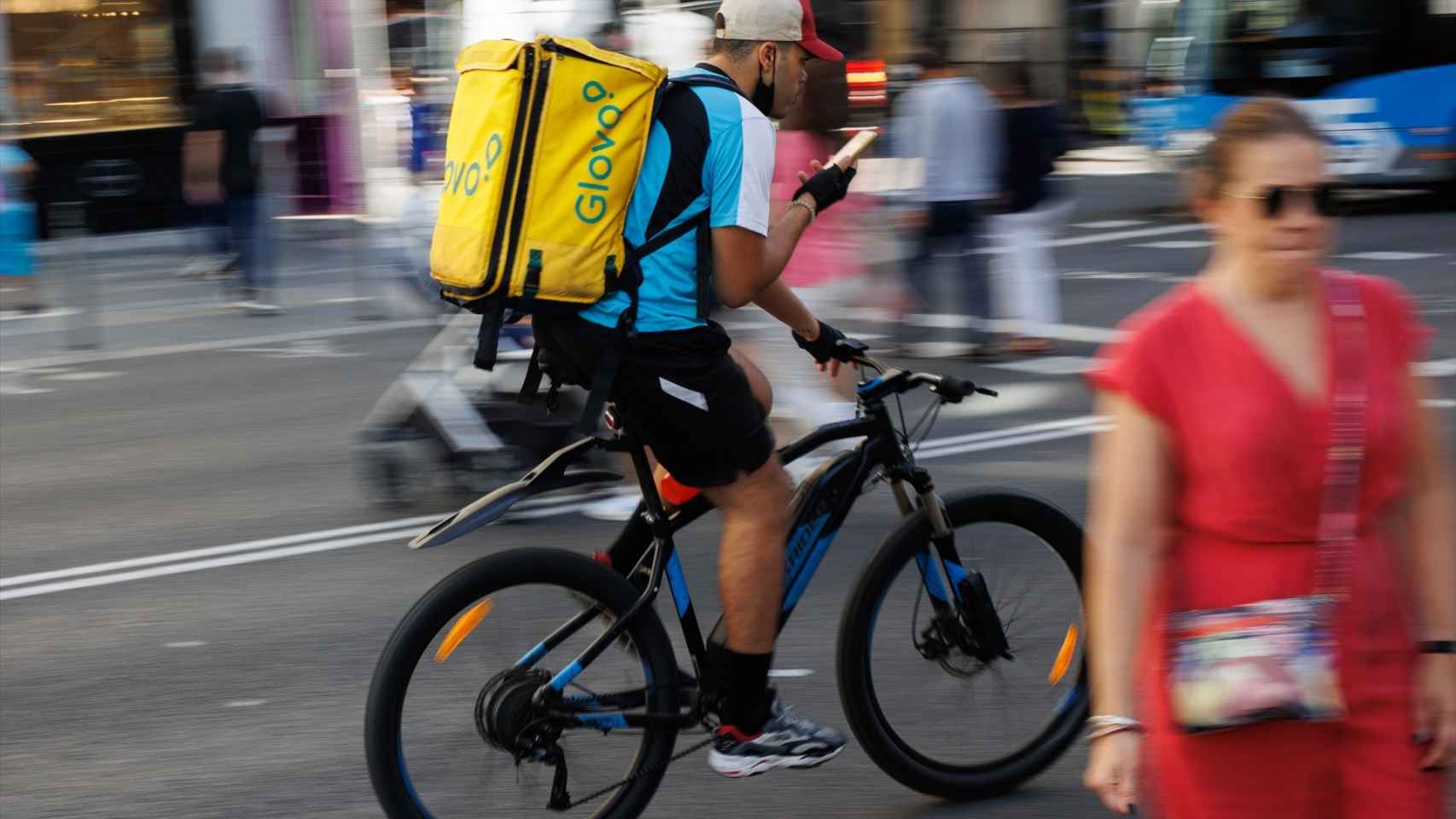Un repartidor de Glovo en bicicleta por una calle del centro de Madrid.