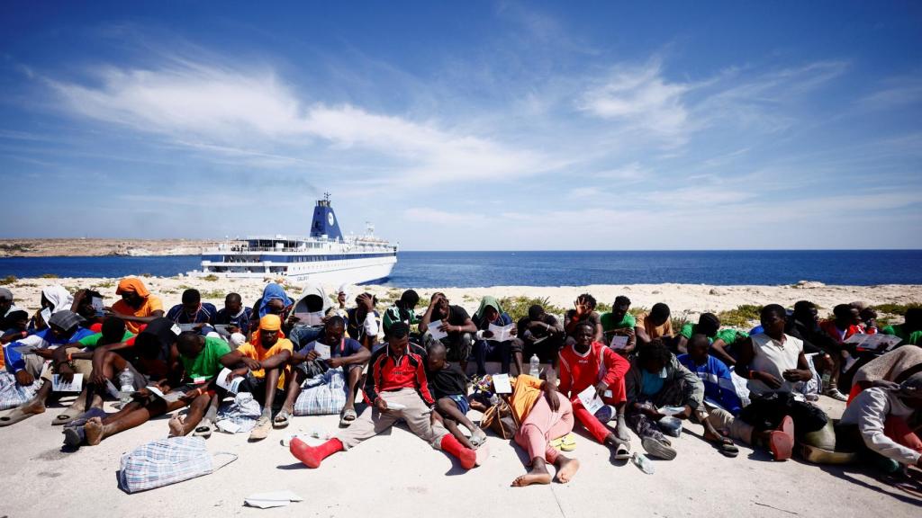 Los migrantes esperan cerca del puerto para ser trasladados al continente, en la isla siciliana de Lampedusa.