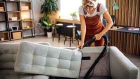 Imagen de archivo de una mujer limpiando un sofá. Foto: iStock.