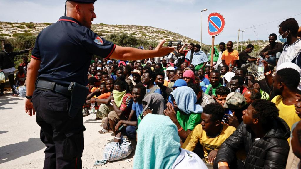 Un miembro de los Carabinieri hace gestos hacia los migrantes fuera del punto de acceso, en la isla siciliana de Lampedusa, Italia, el 16 de septiembre de 2023.