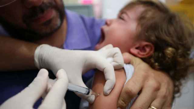 Un sanitario poniendo una vacuna a una niña pequeña.