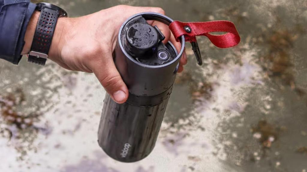 Una persona sujetando la botella mostrando su botón.