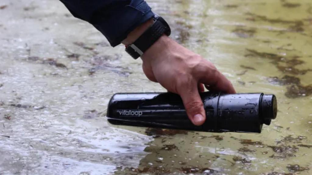 Una persona cogiendo agua de un río con la botella.