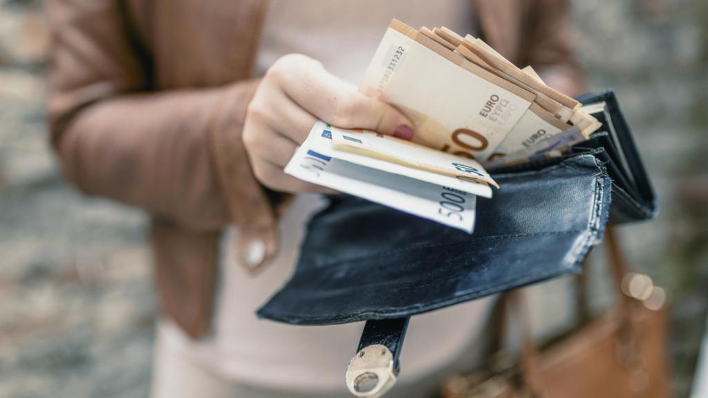 Una mujer pagando con billetes.