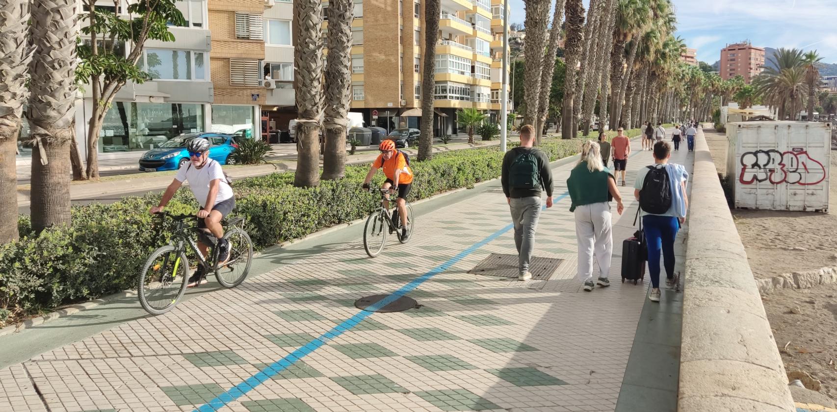 Dos bicis y varios peatonales, en el Paseo Marítimo Pablo Ruiz Picasso de Málaga.