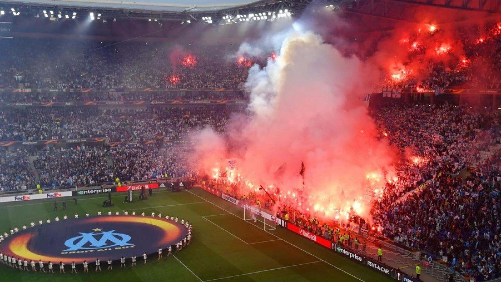Los ultras del Marsella lanzan bengalas al terreno de juego durante un partido.