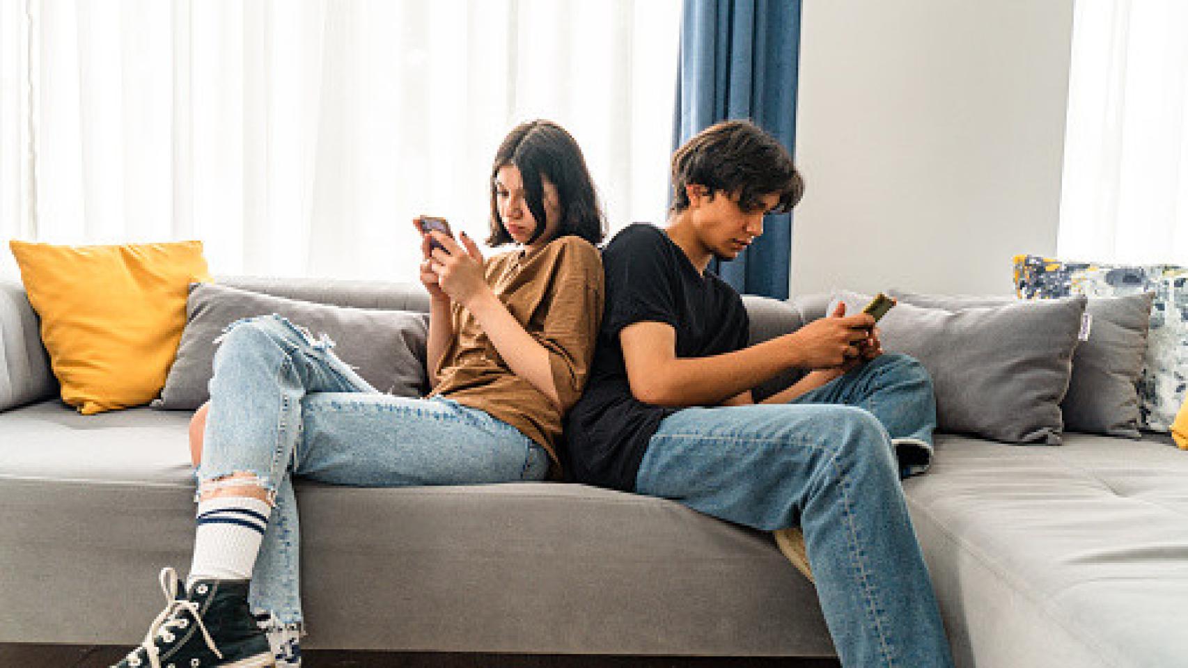 Imagen de una pareja  joven dándose la espalda mirando el móvil.