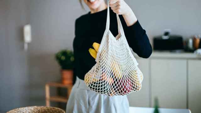 Imagen de una mujer sujetando una bolsa con verduras.