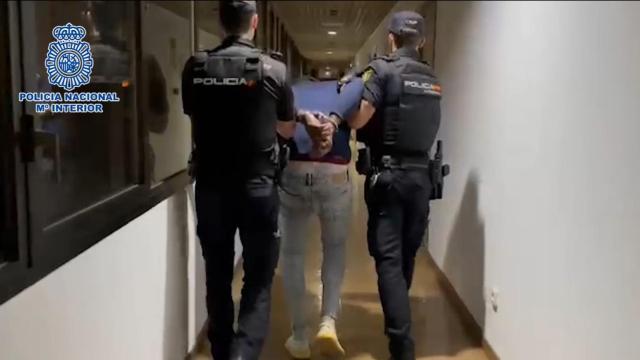 El presunto asesino detenido y trasladado por dos policías nacionales.