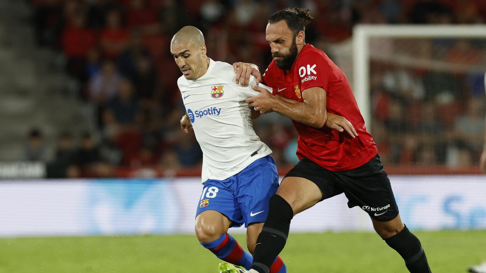 Muriqi y Romeu pelean un balón