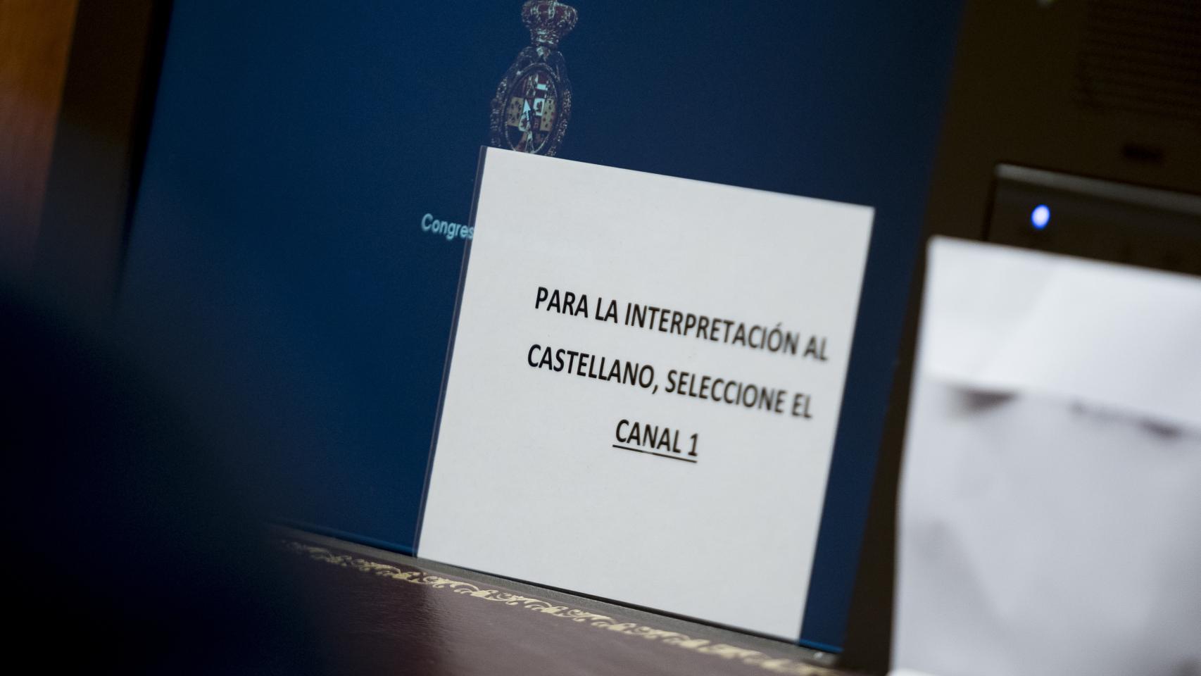 Un cartel para el uso de pinganillos durante la primera sesión del debate de investidura del líder del PP, en el Congreso de los Diputados.