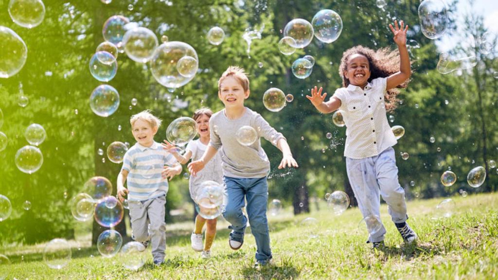 Niños jugando con pompas de jabón.