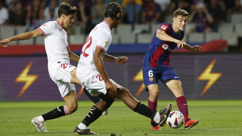 Gavi da un pase ante la oposición de los jugadores del Sevilla.