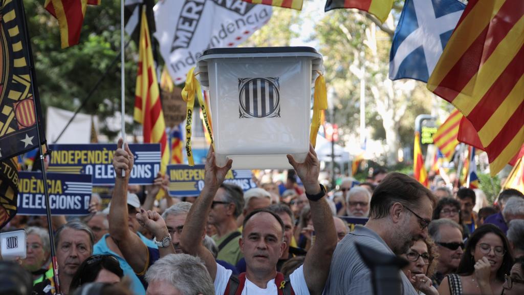 Manifestante alzando una urna en la manifestación de la ANC por el sexto aniversario del 1-O.