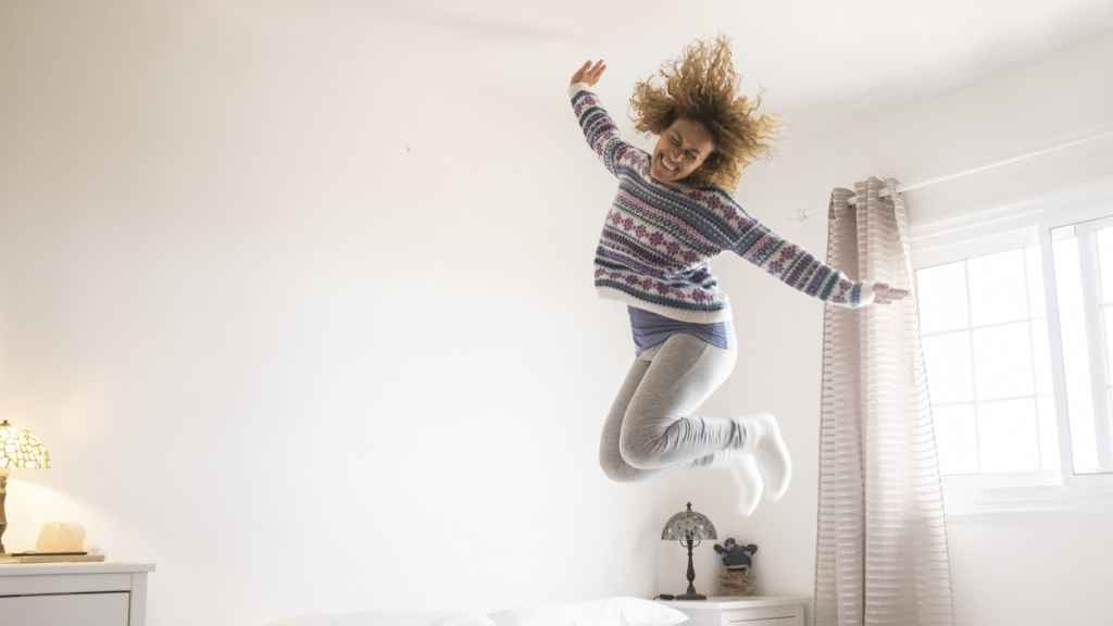 Imagen de archivo de una mujer saltando sobre la cama. Foto: iStock.