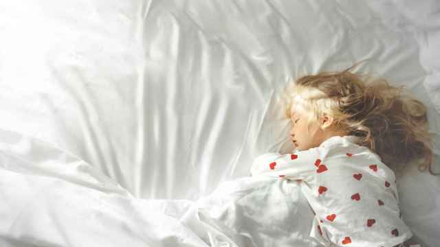 Imagen de archivo de una niña pequeña durmiendo sola.