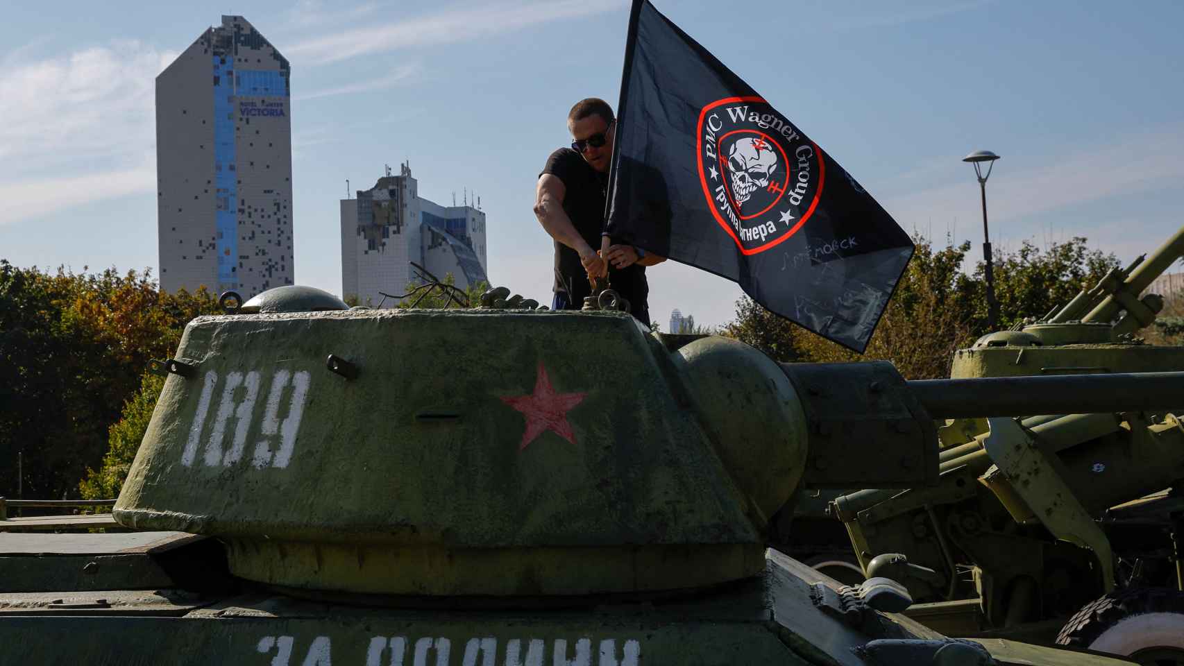 Un hombre coloca una bandera en un tanque de la era soviética en un memorial improvisado para Prigozhin.