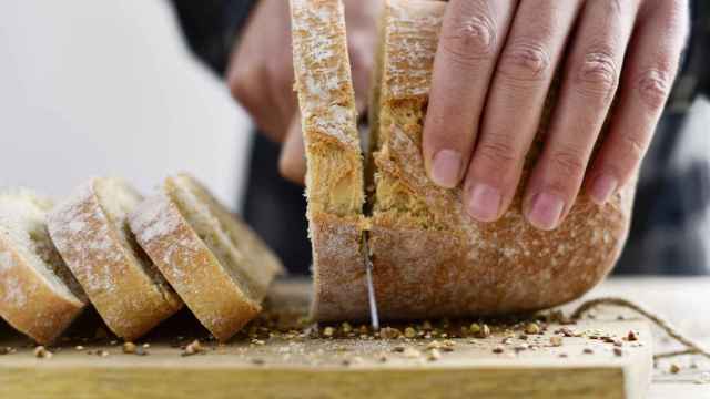 Imagen de archivo de una persona cortando pan.
