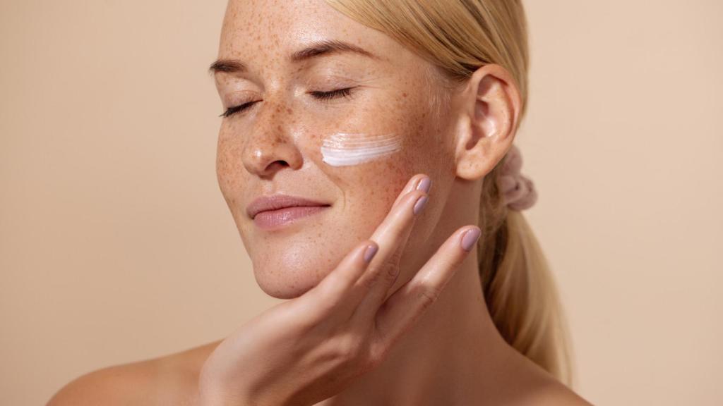 Mujer sonriente con crema en el rostro.