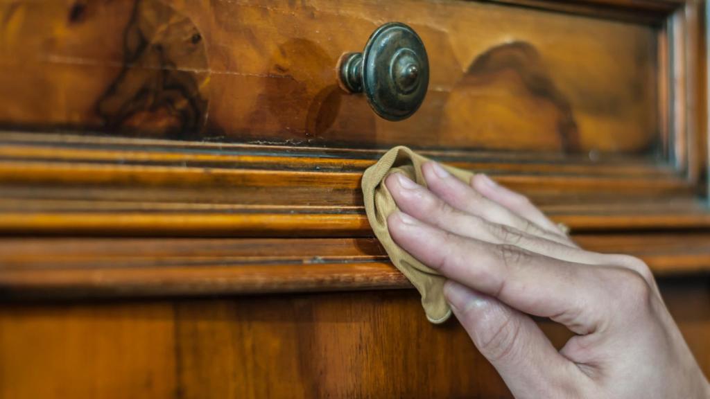 Imagen de una persona limpiando un mueble de madera.