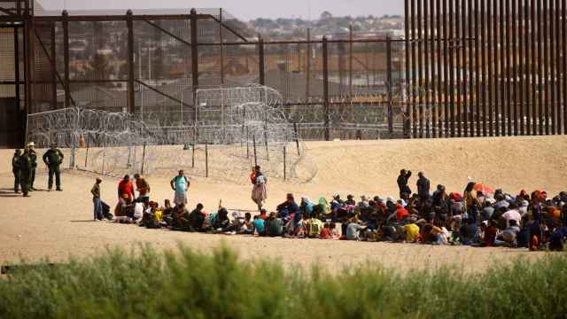 Migrantes se reúnen cerca del muro fronterizo después de cruzar el río Bravo, visto desde Ciudad Juárez.