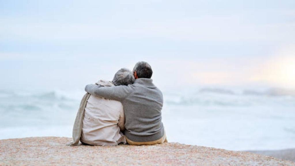 Una pareja de jubilados sentados frente al mar
