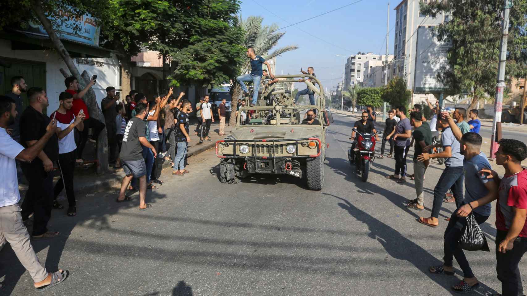 Un grupo de hombres gazatíes celebra junto a un vehículo militar israelí capturado por los atacantes.
