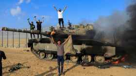 Palestinos celebran mientras un vehículo militar israelí arde después de ser atacado