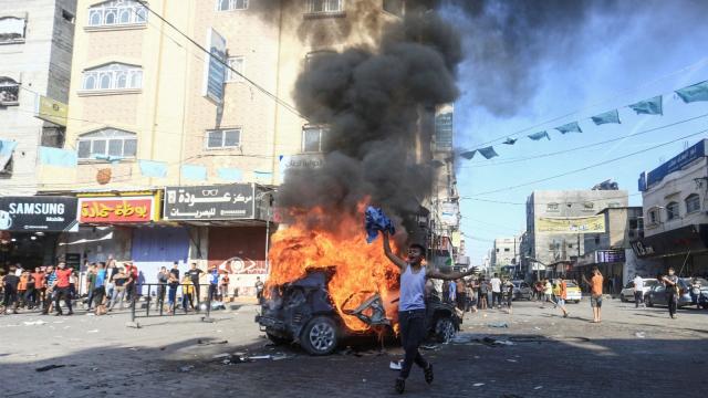 Un niño palestino celebra la ofensiva de Hamás frente a un coche israelí en llamas, este sábado en Gaza.