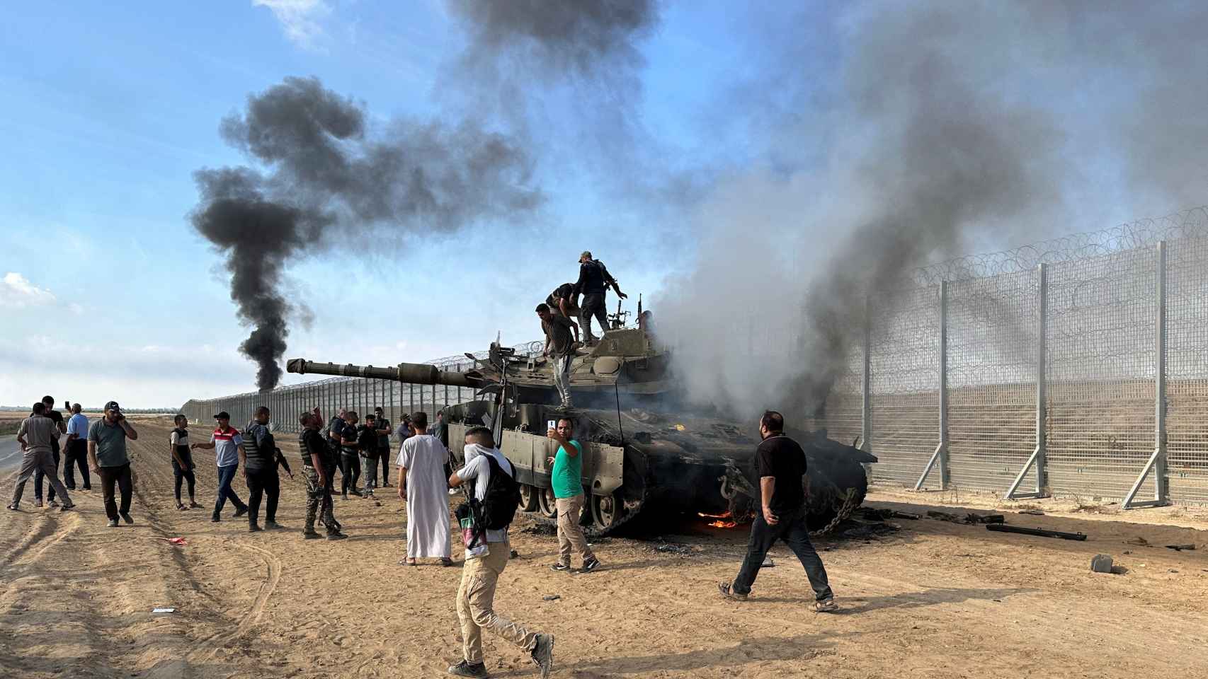 Un grupo de palestinos celebra la quema de un vehículo militar israelí, el sábado en Gaza.