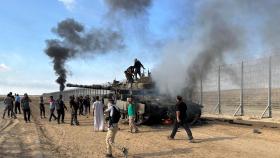 Un grupo de palestinos celebra la quema de un vehículo militar israelí, el sábado en Gaza.