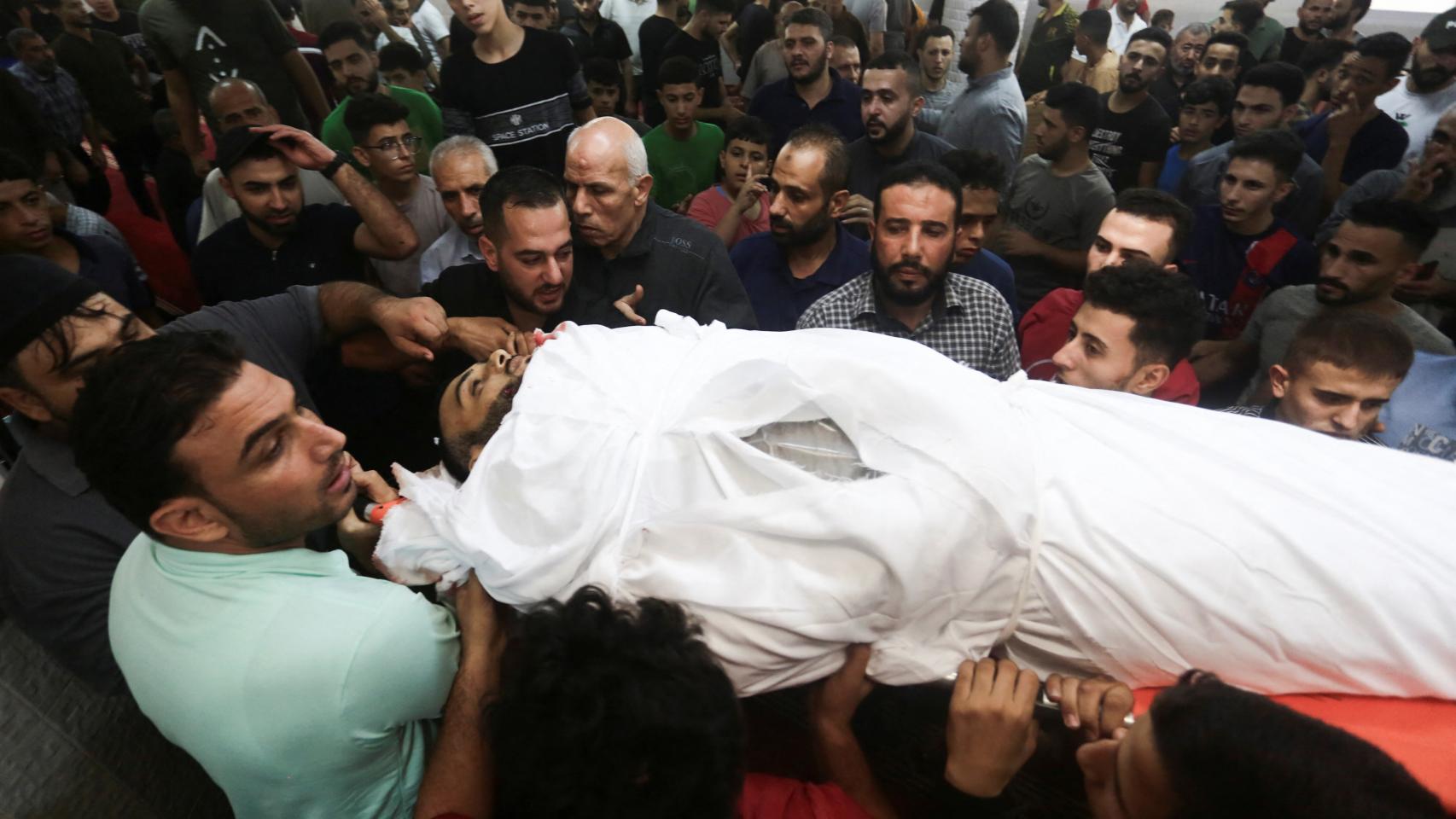 Palestinos trasladan el cuerpo amortajado de una persona muerta en un ataque israelí.