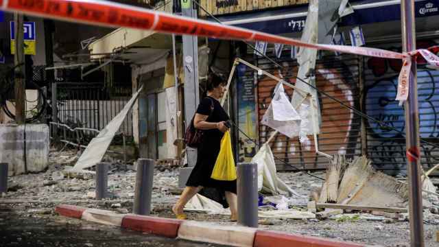 Una mujer camina entre los escombros provocados por un cohete, en Tel Aviv.
