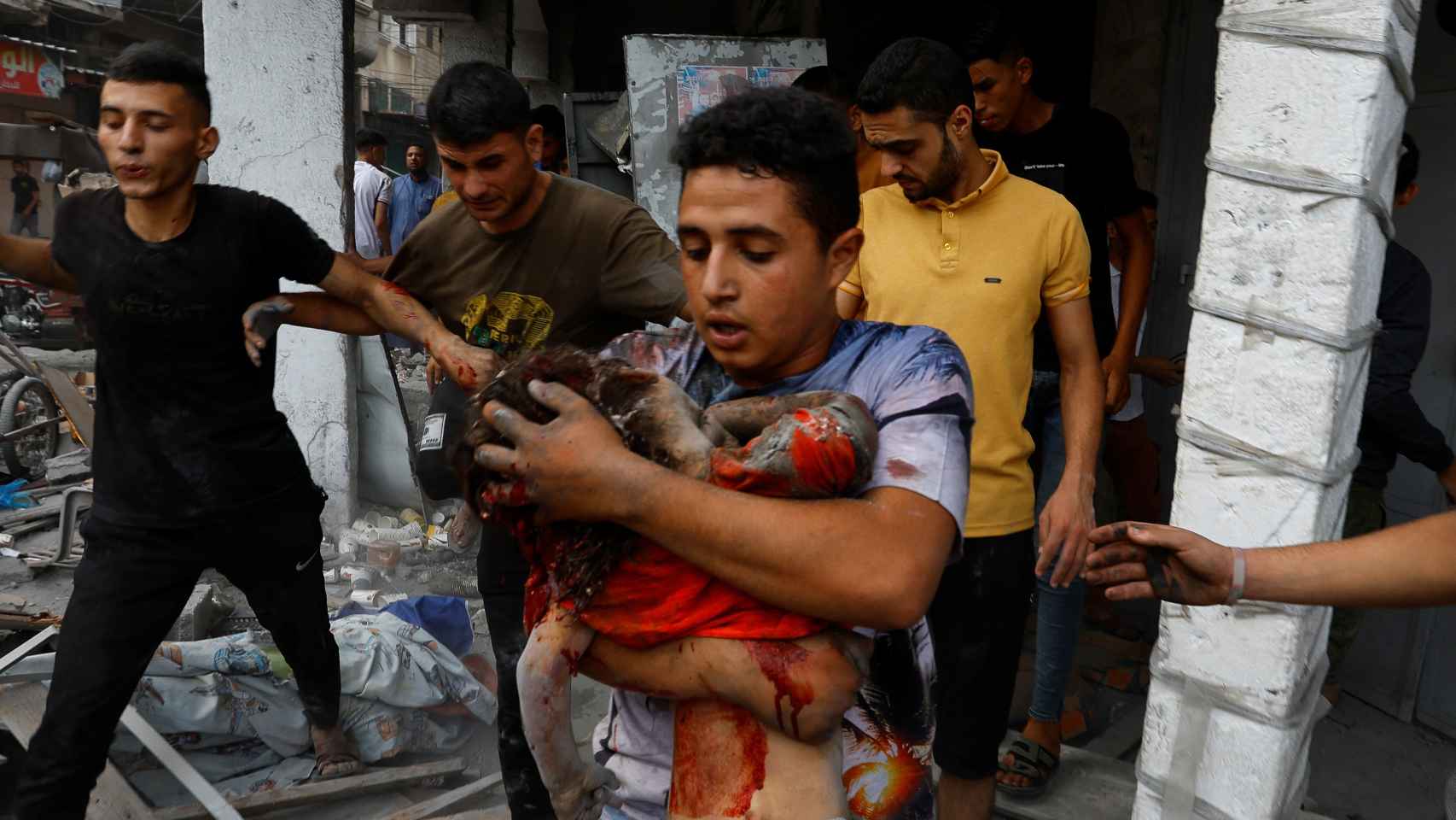 Un hombre carga el cadáver de una niña sacada de debajo de los escombros de un edificio de Gaza.