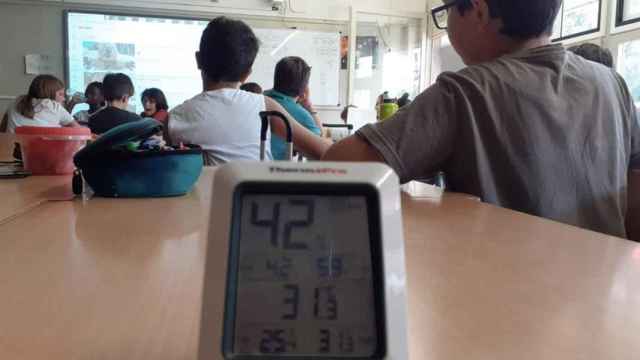 Varios niños con un termómetro en clase.
